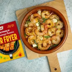 Soczyste krewetki z czosnkiem i ziołami w naczyniu, obok przyprawa Prymat do Air Fryer.
