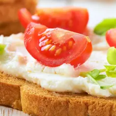 Chrupiąca grzanka z kremowym serkiem ricotta, świeżymi pomidorkami i zielonymi kiełkami. Pyszna i lekka przekąska.