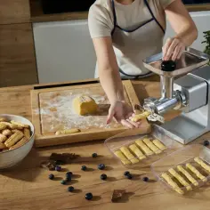 Jak założyć końcówkę do ciastek na maszynkę? Kobieta pokazuje, jak przygotować ciasto na ciasteczka i używa maszynki do ich formowania.