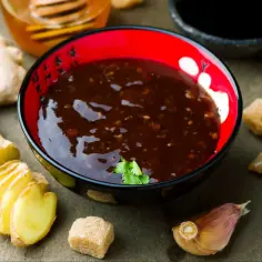 Sos teriyaki do czego? Aromatyczny sos w miseczce, obok imbir, czosnek i cukier. Idealny do marynowania mięs i warzyw.