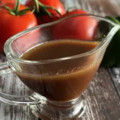 Sos balsamiczny w sosjerce, na tle pomidorów i papryki.