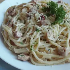 Spaghetti carbonara - przepis oryginalny ze śmietaną. Pyszne danie z makaronem, boczkiem i parmezanem, udekorowane natką pietruszki.