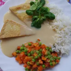 Talerz z ryżem, sosem, warzywami i dwoma kawałkami smażonego sera.