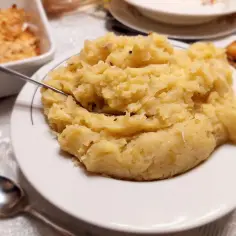 Panczkraut, czyli ziemniaki z kapustą, na talerzu. Obok pieczone mięso i zapiekanka.