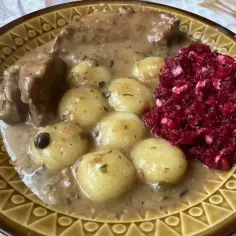 Talerz z kluskami śląskimi, mięsem w sosie i surówką z buraków.