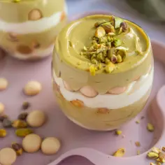 Pyszny deser w pucharku: krem pistacjowy z mascarpone, przełożony biszkoptami i posypany pistacjami.