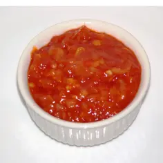 Czerwony sos piri piri w białej miseczce.