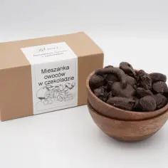 Pudełko z napisem "Mieszanka owoców w czekoladzie" obok drewnianej miseczki pełnej ciemnych, oblanych czekoladą owoców.