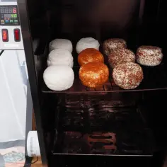 Wędzone serca, w tym ser typu włoskiego, w wędzarni. Niektóre okrągłe sery są białe, inne pokryte przyprawami.