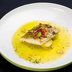 Filet ryby z ziemniakami w żółtym sosie z ziołami i pomidorkami.