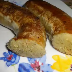 Dwie pieczone kiszki ziemniaczane na talerzu z kwiatowym wzorem.