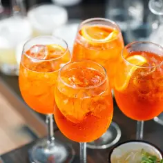 Cztery orzeźwiające drinki Aperol Spritz z lodem i plasterkiem pomarańczy. Idealne na letnie popołudnie.