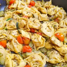 Tortellini z mięsem, cukinią i pomidorkami koktajlowymi w sosie.