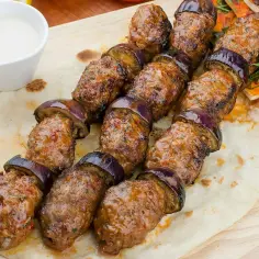 Kofta kebab z bakłażanem na chlebku pita, podany z sosem i sałatką. Pyszne danie, które zachwyci każdego smakosza.