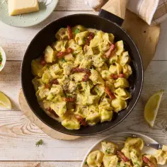 Tortellini z mięsem w kremowym sosie, posypane parmezanem i boczkiem. Podane z cytryną i koperkiem. Idealne na obiad.