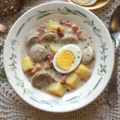 Miseczka żurku z kiełbasą, ziemniakami, jajkiem i chlebem.