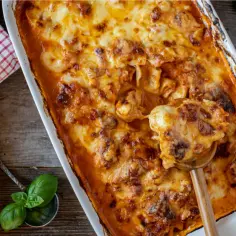 Zapiekanka z tortellini z grzybami, polana sosem i zapieczona z serem.