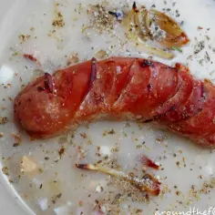 Kiełbasa grillowana w zupie z dodatkiem jajka i cebuli, posypana przyprawami.