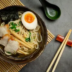 Apetyczny ramen z plastrami wieprzowiny, jajkiem na pół, bambusem i nori. Idealny przepis, jak zrobić ramen.