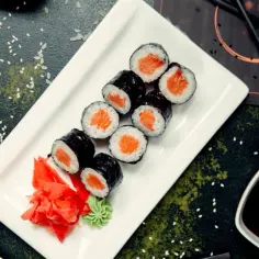 Pyszne hosomaki z łososiem, podane z imbirem i wasabi na białym talerzu.