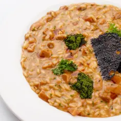 Kremowe risotto z grzybami, ozdobione zieloną posypką i chrupiącym czarnym elementem. Idealny ryż do risotto.