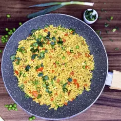 Aksamitny ryż z curry, groszkiem i papryką, posypany szczypiorkiem, gotowy do podania.