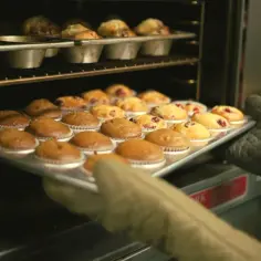 Rękawice wyjmują z piekarnika blachę z muffinkami, które idealnie nadają się do przepisu na wilgotne i puszyste muffinki.