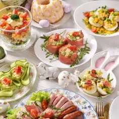 Wielkanocny stół z tradycyjnymi potrawami: jajka faszerowane, roladki z szynki, sałatka, babka i żurek.