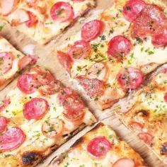Pyszne kawałki pizzy z kiełbasą i serem, idealne na rodzinny obiad. Ten przepis na ciasto do pizzy jest prosty i szybki!