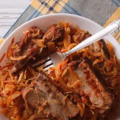 Żeberka w kiszonej kapuście z widelcem w talerzu.