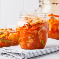 Słoiki i naczynie z pikantnym, fermentowanym kimchi. Zastanawiasz się kimchi co to? To tradycyjna koreańska kiszonka.