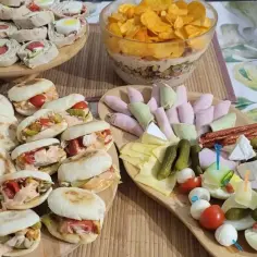 Stół z przekąskami: mini kanapeczki, roladki, ser, wędliny, jajka i chipsy.