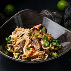 Pyszny makaron udon z wołowiną i warzywami, posypany szczypiorkiem i sezamem. Idealny przepis na szybki obiad.