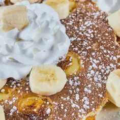 Puszysty omlet bananowy z bitą śmietaną i cukrem pudrem.