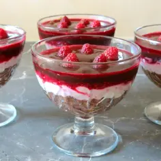 Warstwowy deser w pucharkach: kruche ciasto, krem z mascarpone, polewa wiśniowa i maliny. Pyszny makaron z mascarpone.