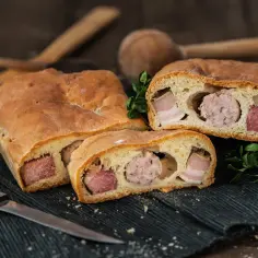 Murzin wielkanocny z widocznym mięsem i kiełbasą w środku, na czarnym obrusie.