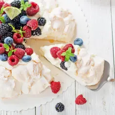 Beza pavlova która zawsze wychodzi, udekorowana bitą śmietaną i świeżymi owocami leśnymi.