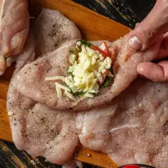 Przygotowanie roladki z kurczaka z serem i ziołami na desce.