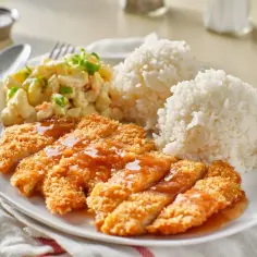 Chrupiący kurczak w panko polany sosem, podany z ryżem i sałatką makaronową. Pyszny obiad!
