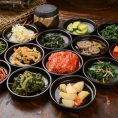 Bogactwo koreańskich banchan: kimchi, marynowane warzywa, sałatki z ziół i kiełków fasoli.