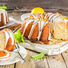 Wilgotna babka cytrynowa z lukrem i czekoladą, ozdobiona miętą i cytryną.