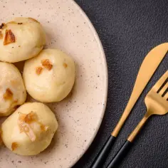 Porcja klusek śląskich z cebulką, idealnych na obiad. Zastanawiasz się, ile kcal ma kluska śląska?