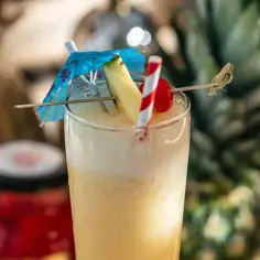 Schłodzony koktajl Piña Colada z ananasem, wiśnią i parasolką.
