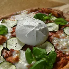 Pyszna pizza z burrata, cukinią i bazylią, pachnąca latem.