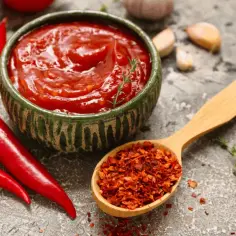 Miseczka sosu meksykańskiego, papryczki chili, łyżka płatków chili i czosnek.