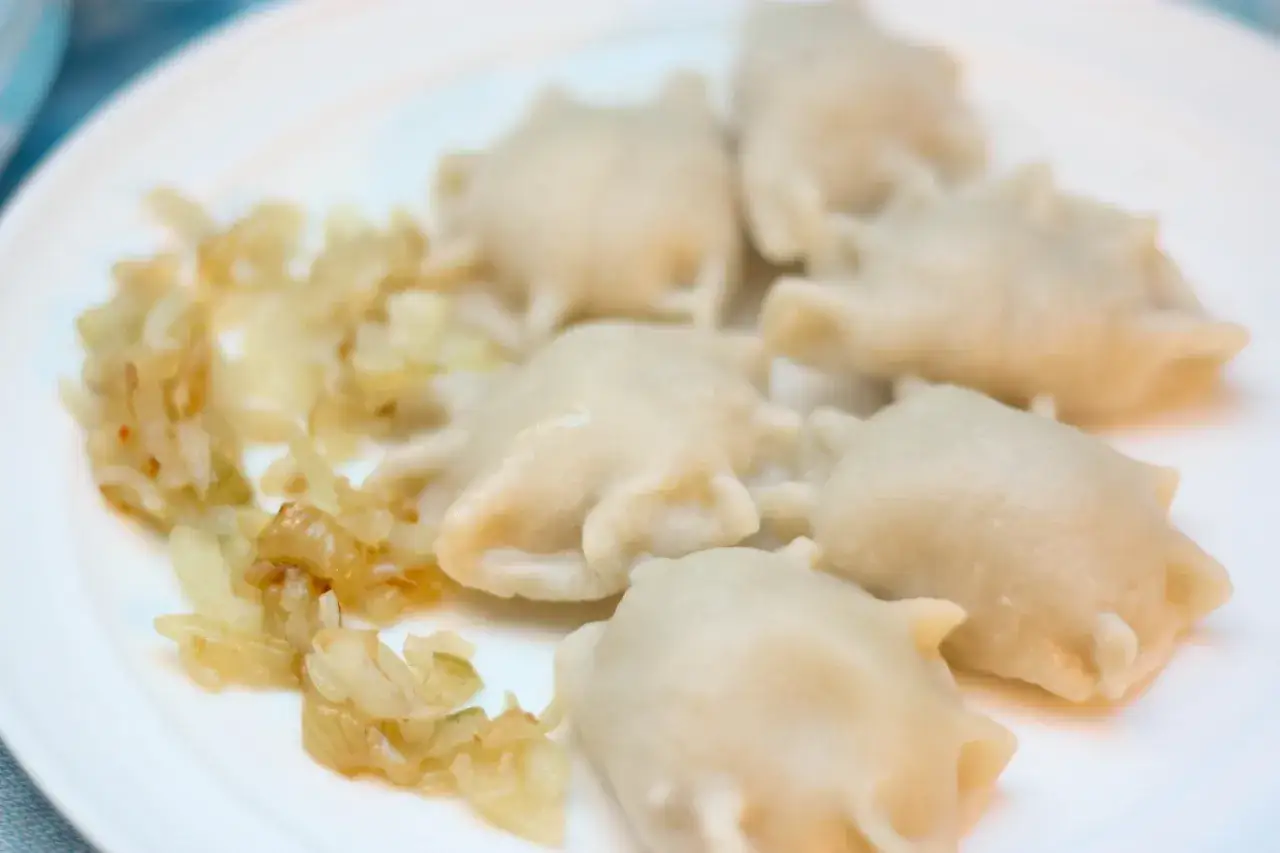 Pyszne pierogi z farszem na mięsie mielonym, podane z podsmażoną cebulką.