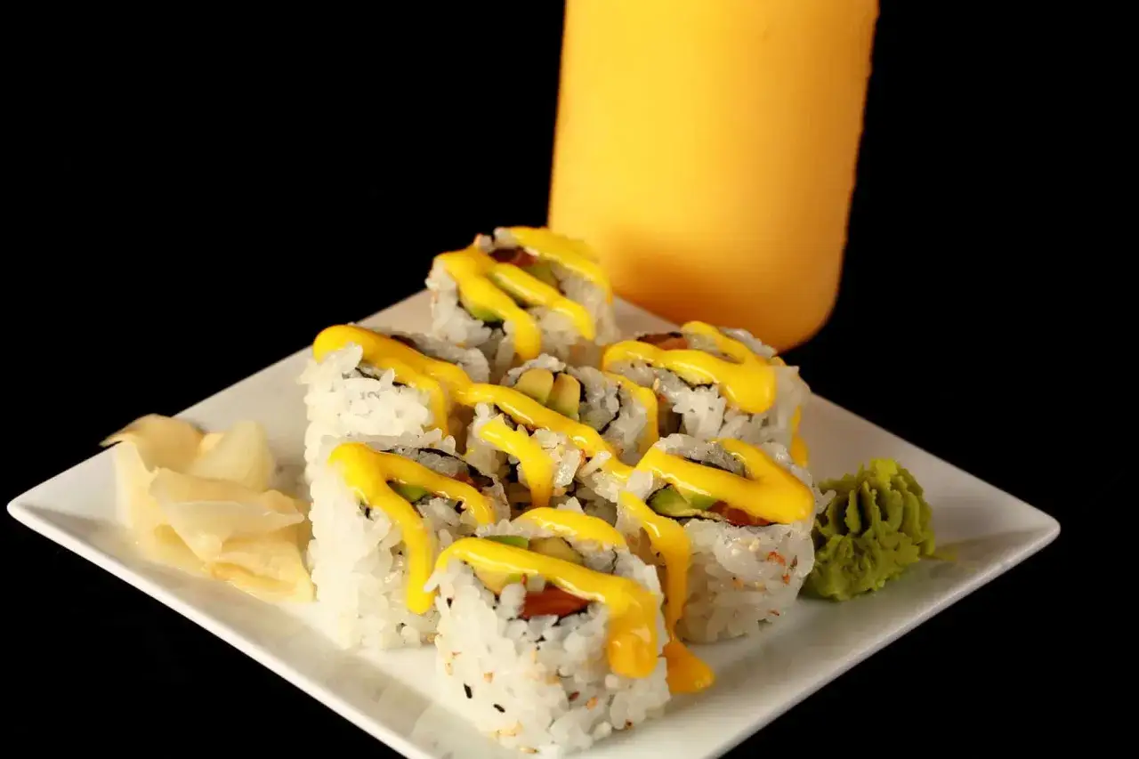 Roladki sushi polane żółtym sosem, obok imbir i wasabi. Idealny sos do sushi podkreśla smak.