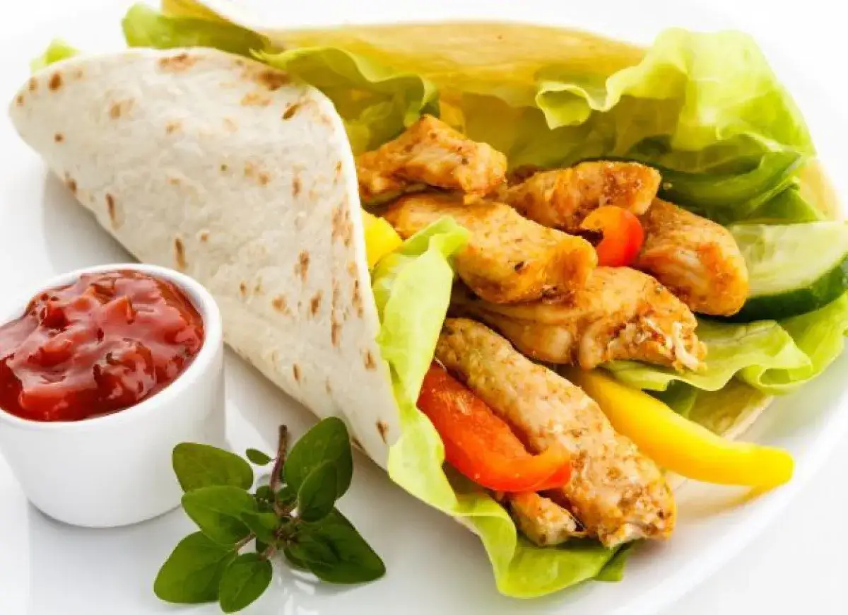 Pyszny, domowy kebab z kurczaka w tortilli, z chrupiącą sałatą, papryką i sosem.