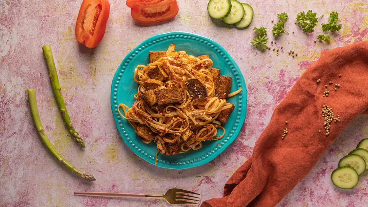Pyszny makaron z tofu, podany z pomidorem, ogórkiem i szparagami. Idealny posiłek dla wegan.