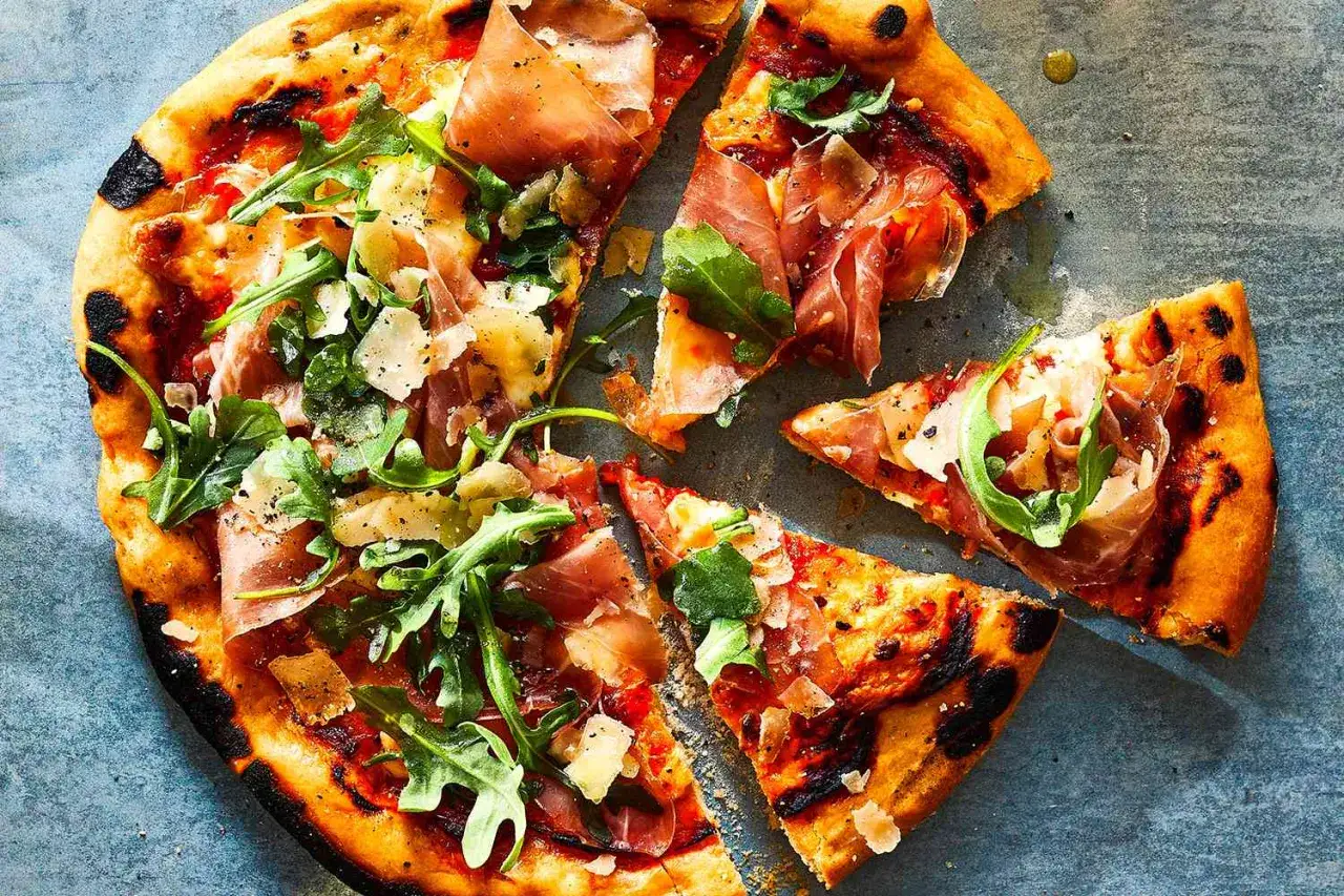 Pyszna pizza parma z rukolą i parmezanem, z chrupiącym, lekko przypalonym brzegiem. Idealna na włoską ucztę.